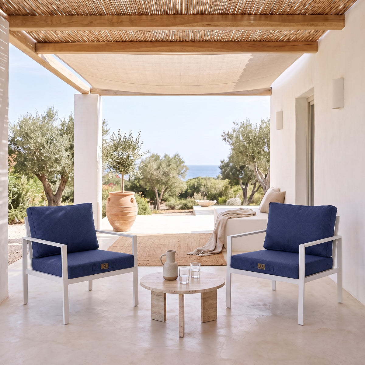 Cuscini per poltrona effetto lino Blu Indaco su due poltrone bianche sotto una pergola coperta, terrazza luminosa al riparo dal sole