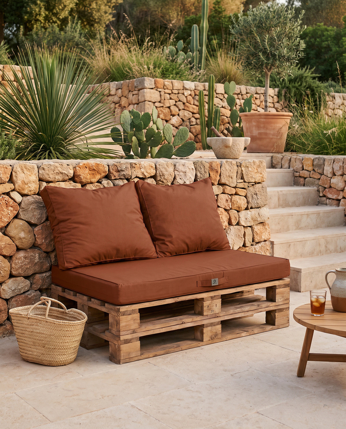 Cuscini per pallet sfoderabili terracotta Deco Arts su due pallet, davanti a un muro a secco a Maiorca