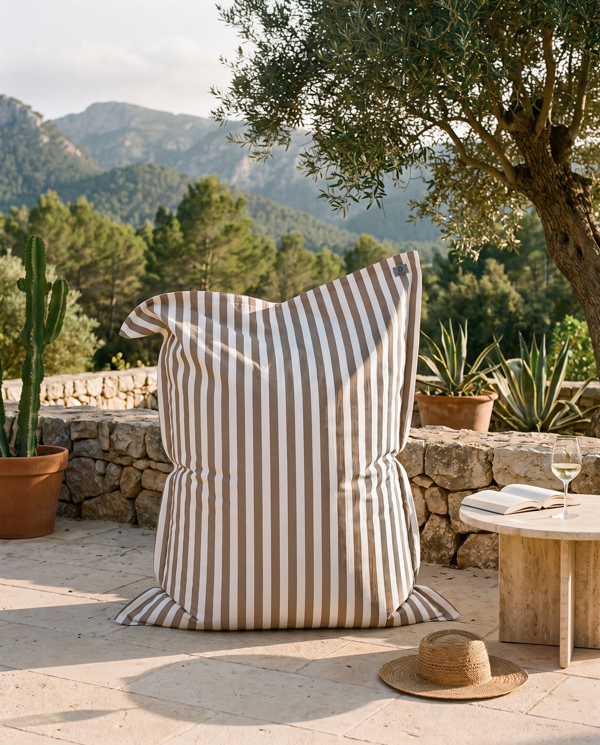 Pouf gigante a righe beige Deco Arts sulla terrazza di una finca a Maiorca, ulivo e montagne