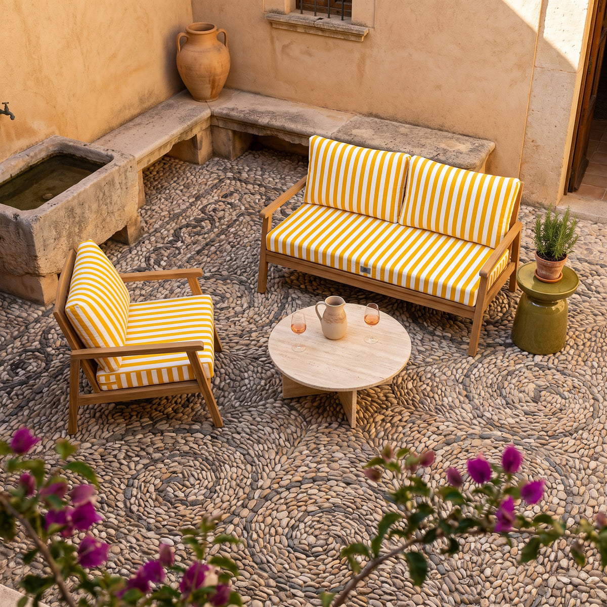 Poltrona e divano in teak con cuscini a righe gialle e bianche Deco Arts in un cortile acciottolato a Maiorca