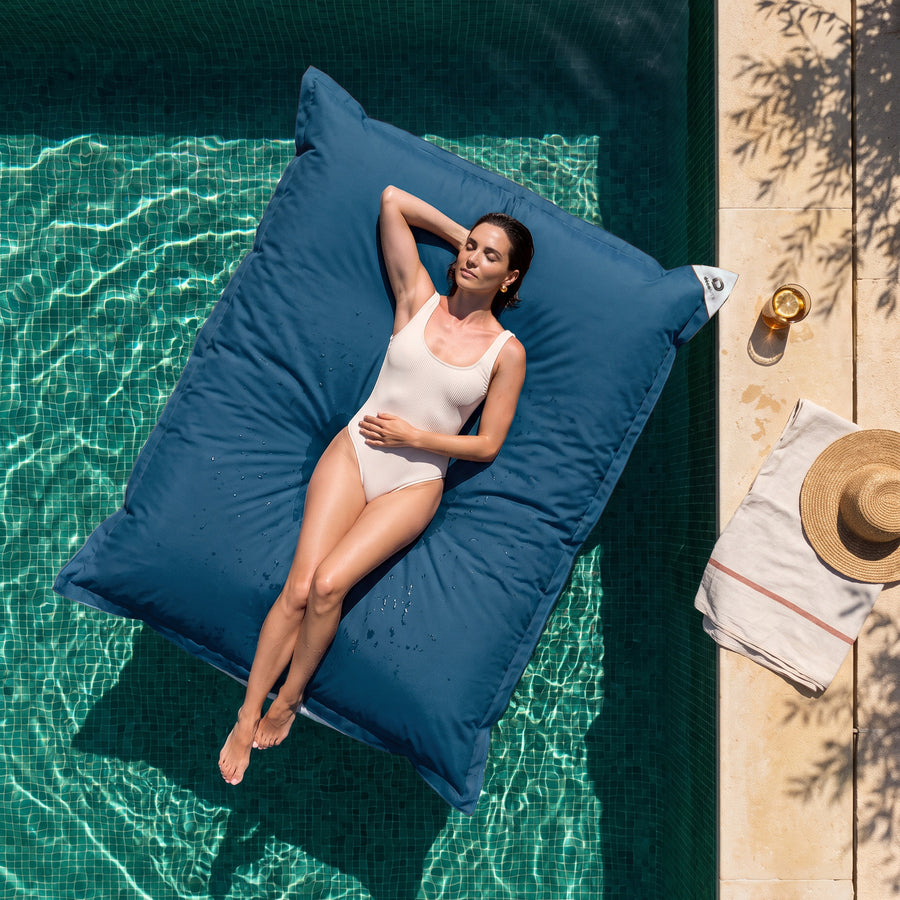 Solo fodera, da riempire – Pouf galleggiante gigante 180 × 140 cm Blu Petrolio in piscina, donna sdraiata al sole, vista dall'alto