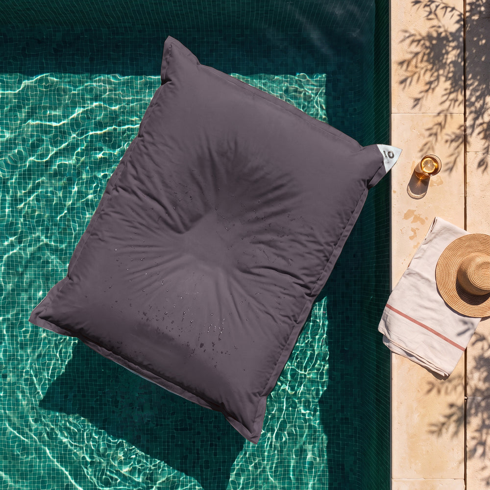 Solo fodera, da riempire – Pouf galleggiante gigante Grigio Carbone sull'acqua di una piscina, vista dall'alto